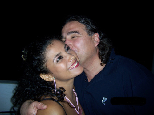 A smiling Latina is being kissed on the cheek by her foreign lover